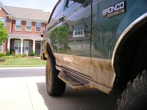 1996 Ford Bronco - Mud-splattered 1996 Ford Bronco parked in a driveway.