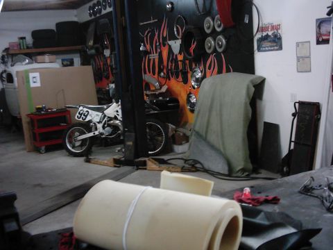 1978 Ford Bronco - A motorcycle is parked in a garage setting, surrounded by various tools and automotive parts.