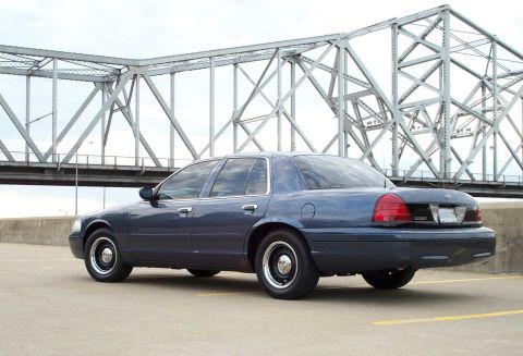 1998 Ford Crown Victoria - Dark blue 1998 Ford Crown Victoria sedan parked outdoors with a bridge in the background.