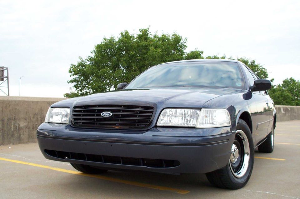 Dark blue Ford Crown Victoria sedan, front 3/4 view, on rooftop parking deck