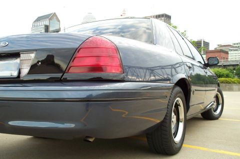 1998 Ford Crown Victoria - Rear 3/4 view of a dark blue 1998 Ford Crown Victoria, chrome wheels and a detailed taillight assembly.