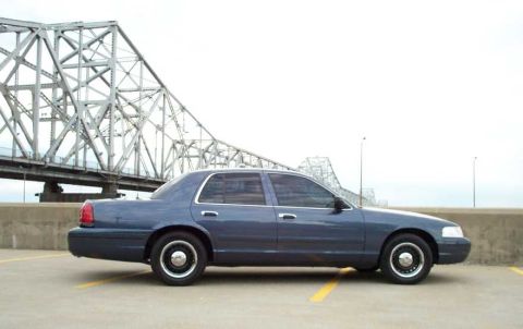 1998 Ford Crown Victoria - A blue Ford Crown Victoria is parked near a large bridge, with a watermark from Supermotors.net visible.
