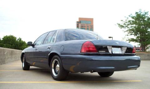 1998 Ford Crown Victoria - Rear view of a dark gray sedan parked outdoors, showing its taillights and trunk.