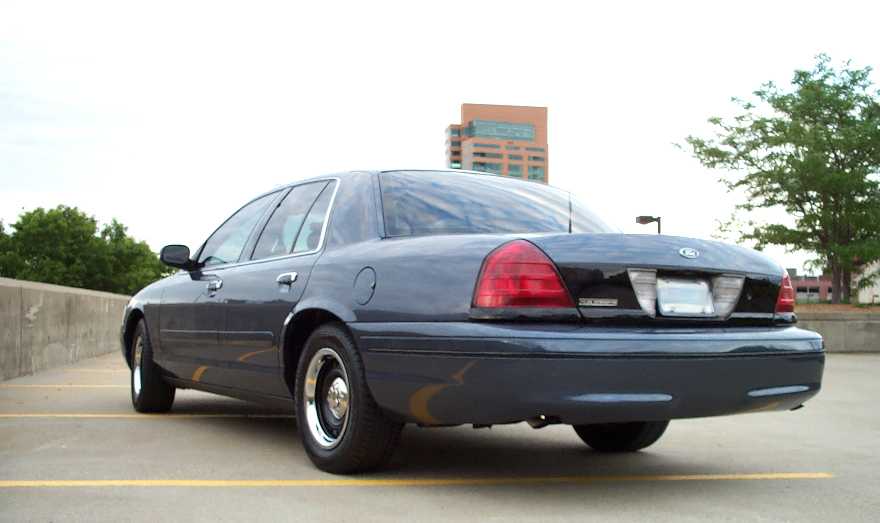Navy Ford Crown Victoria sedan, rear three-quarter view on a rooftop parking deck