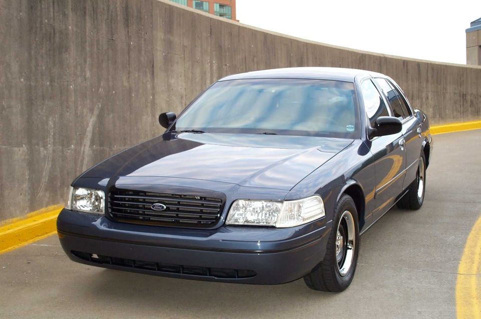 Dark gray Ford Crown Victoria sedan, front 3/4 view on a concrete garage ramp