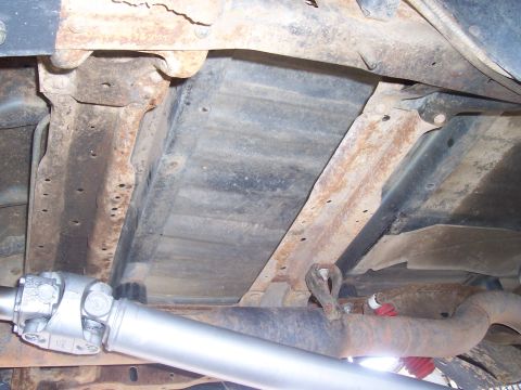 1994 Ford F-150 - The undercarriage of a truck, the driveshaft and exhaust pipe, with visible rust on the frame.
