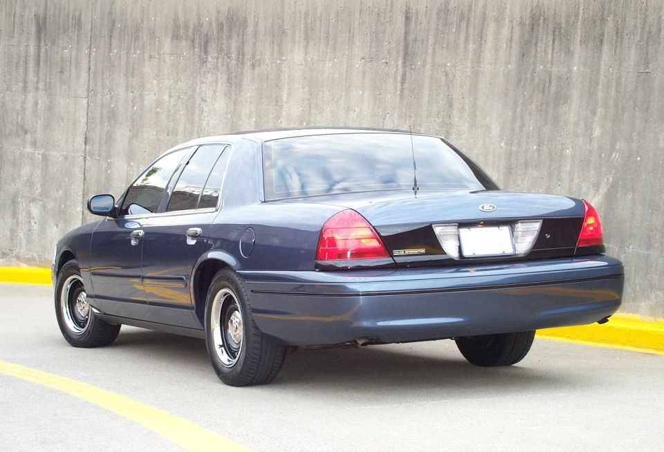 Dark blue Ford Crown Victoria sedan, rear 3/4 view, parked on concrete ramp