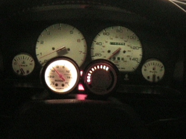 Car dashboard with speedometer, tachometer, boost gauge, temperature gauge, and fuel gauge