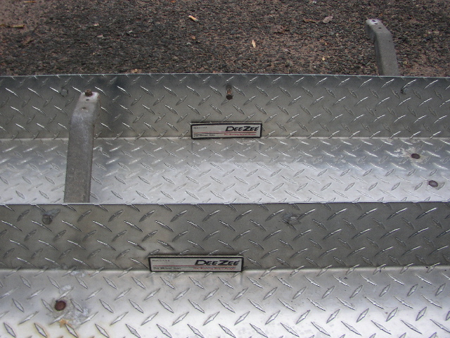 Diamond plate metal with two DeeZee emblems and a Supermotors.net watermark