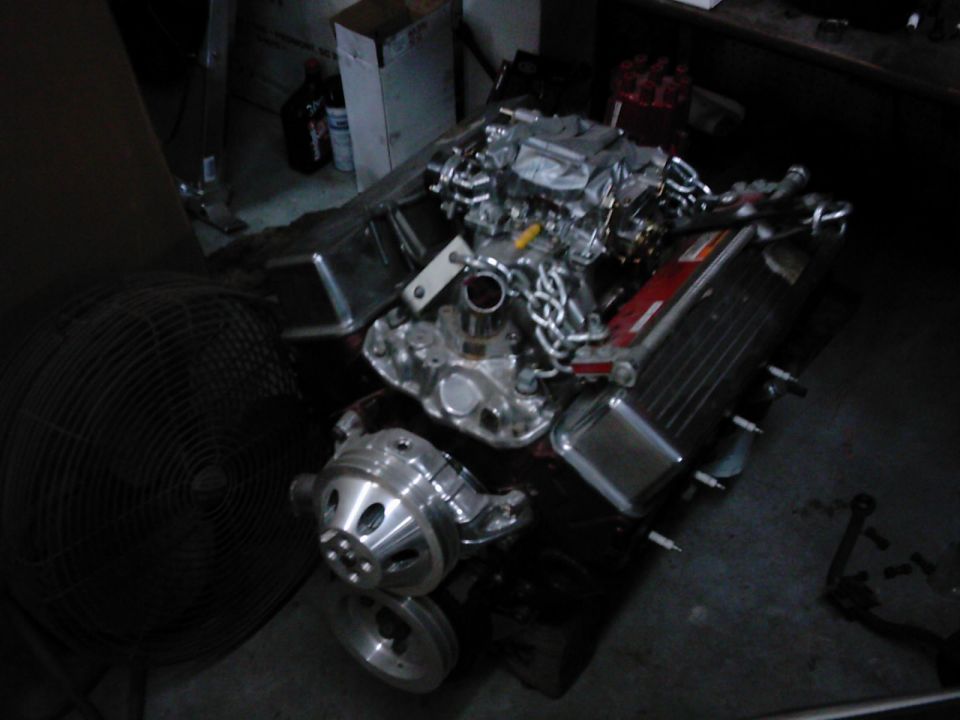 Chrome engine with carburetor and fan pulley, on a dark surface