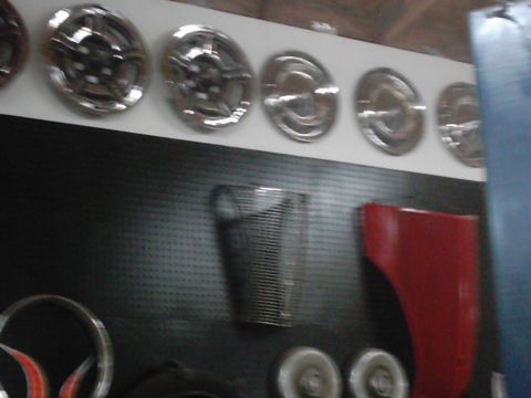 1978 Ford Bronco - Various automotive parts, including hubcaps, a grille, and a red fender, are displayed on a wall.