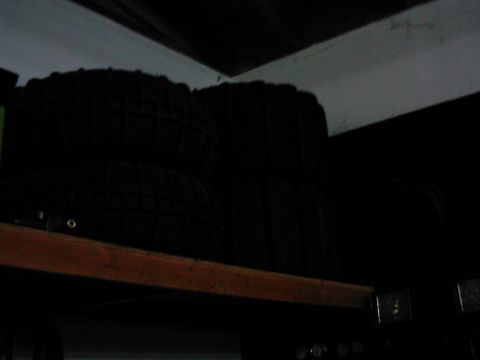 1978 Ford Bronco - Tires are stored on a shelf in a dark room.