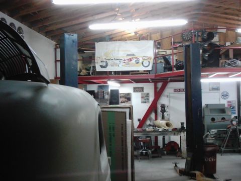 1978 Ford Bronco - Auto repair shop interior with a car body in the foreground and various tools and equipment visible.