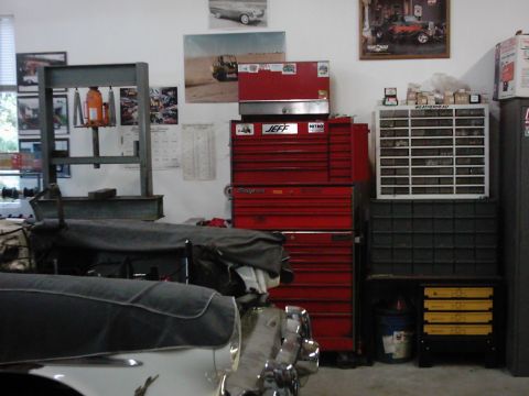 1978 Ford Bronco - A cluttered garage scene displays various tools and automotive parts, with a partially covered vehicle in the foreground.