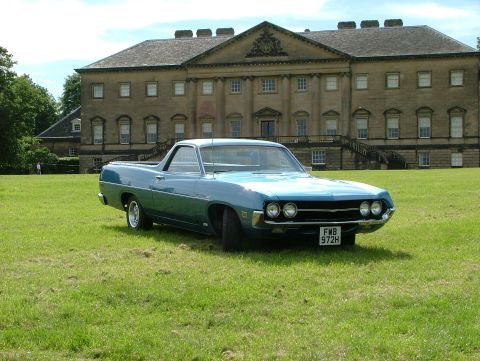 1970 Ford Ranchero - A blue 1970 Ford Ranchero is parked on a lawn in front of a grand estate.
