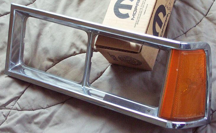 Chrome headlight bezel with amber turn signal housing, Mopar boxes in background