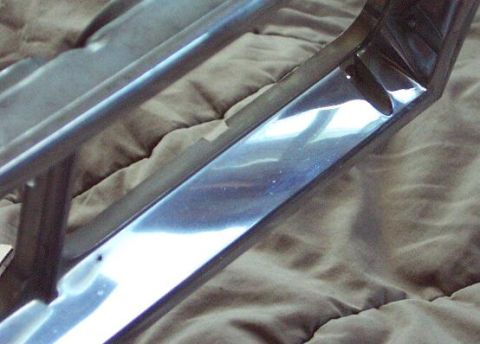1985 Ford LTD Crown Victoria - A close-up view of a chrome trim piece, likely a car part, against a fabric background.