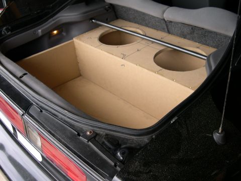 1997 Ford Probe - Custom MDF subwoofer box with two circular cutouts built into a carpeted car trunk, rear seat and antenna visible.