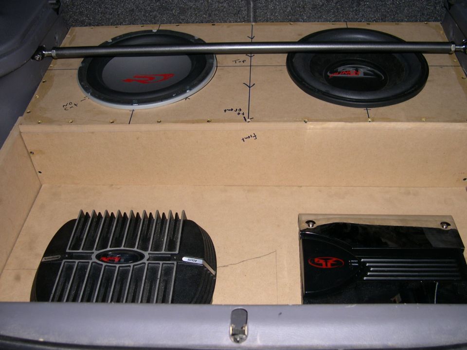 Unfinished MDF subwoofer box with two subs and two Rockford Fosgate amps in a hatchback trunk