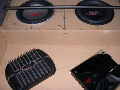 1997 Ford Probe - Overhead close-up of an unfinished MDF audio install: two Rockford Fosgate Punch subwoofers mounted in the raw particleboard top panel with…