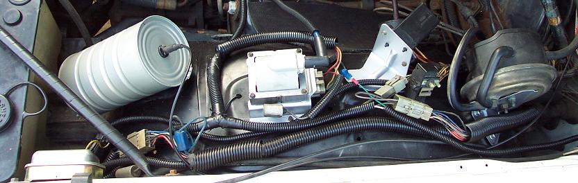 Engine compartment with a cylindrical air filter, ignition coil, and wiring harnesses