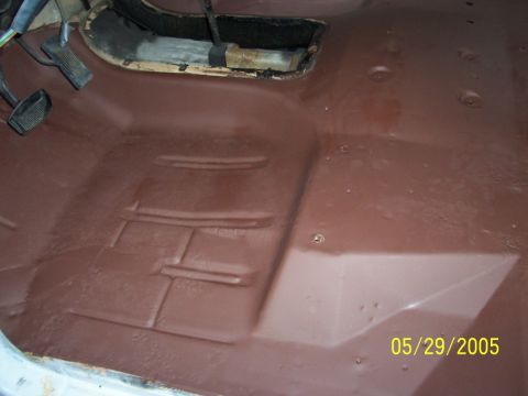1979 Ford Bronco - The interior floor of a vehicle, showing the area around the pedals and the transmission tunnel, coated in a protective substance.