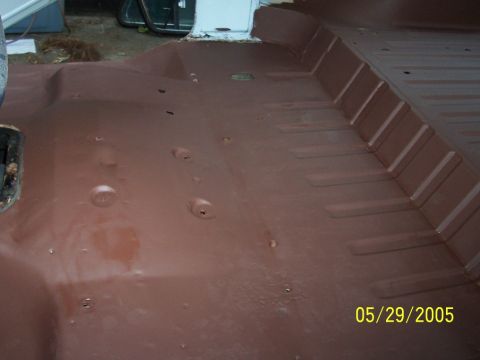1979 Ford Bronco - The interior floor of a vehicle shows a brown coating and numerous mounting points.