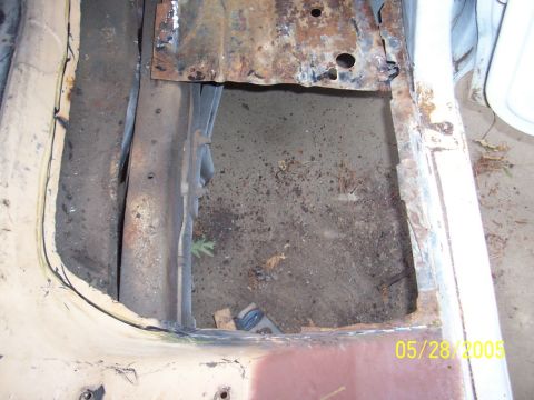 1979 Ford Bronco - The rusted floor pan of a vehicle shows significant damage and debris accumulation.