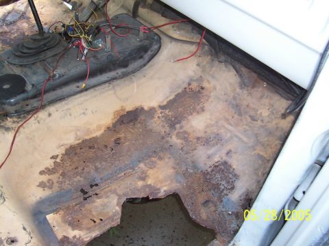 1979 Ford Bronco - The interior floor pan shows significant rust damage and exposed wiring, with a gear shifter visible.