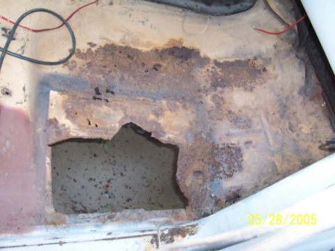1979 Ford Bronco - Vehicle floor pan shows significant rust damage and a hole, with some wiring visible.