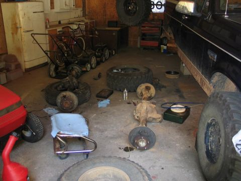 1995 Ford Bronco - A 1995 Ford Bronco is parked in a garage, surrounded by its disassembled axles and tires, suggesting maintenance or modification.