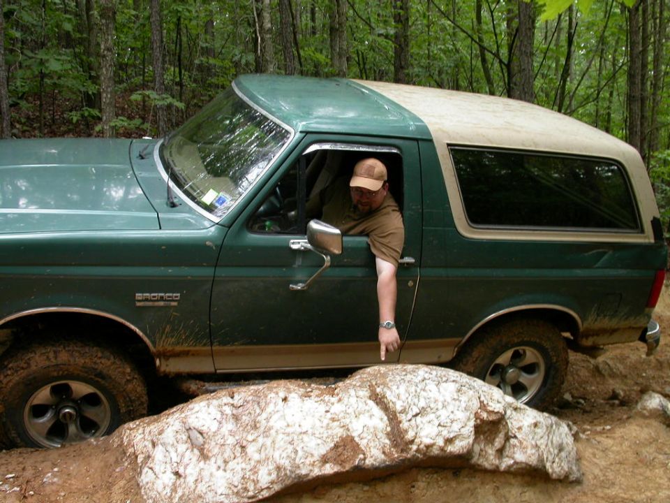 Green 1990 Ford Bronco navigating rocky terrain off-road