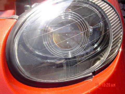 1997 Ford Taurus - Headlight assembly detail on an orange vehicle.