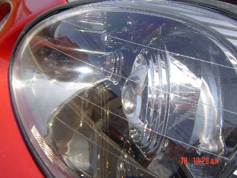 1997 Ford Taurus - A detailed view of a vehicle's headlight, highlighting its internal components and the surrounding red body panel.