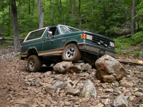 1990 Ford Bronco - This 1990 Ford Bronco tackles a challenging off-road course, demonstrating its capability on rough terrain.