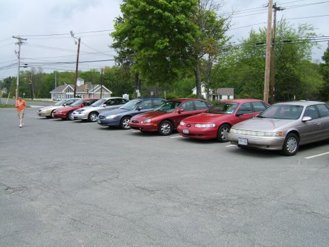 1998 Ford Taurus - A row of sedans, including a 1998 Ford Taurus, parked in a lot on an overcast day.