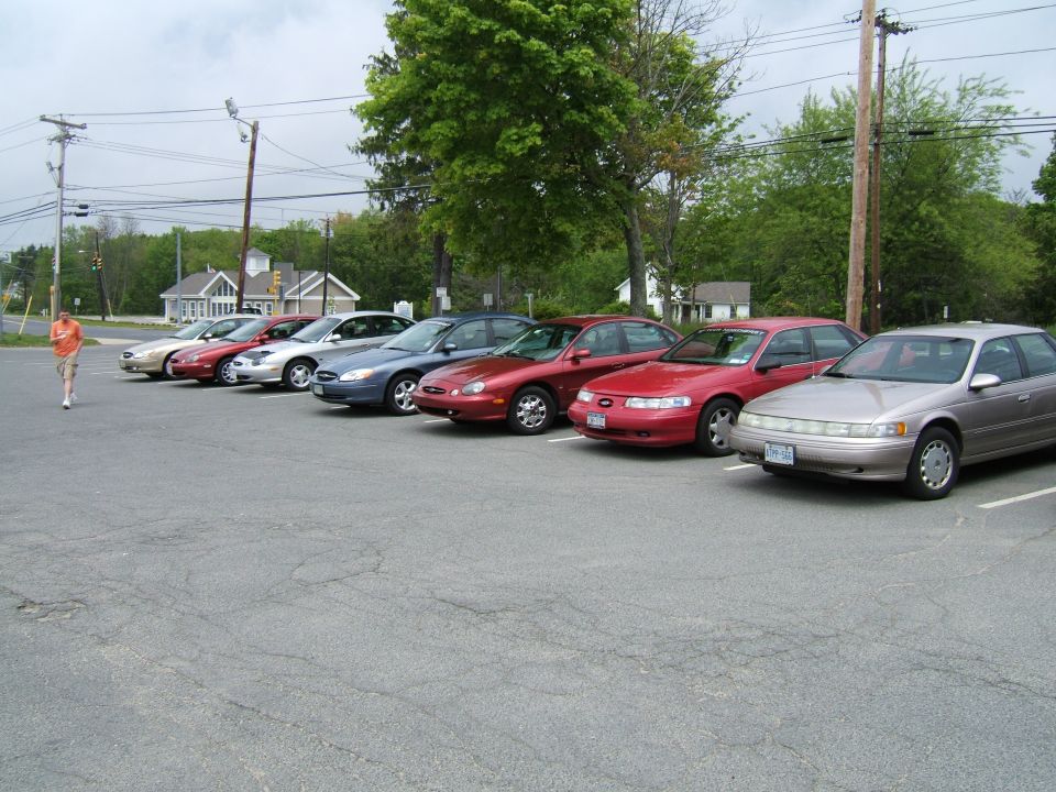 Several sedans parked in a lot, including a 1998 Ford Taurus