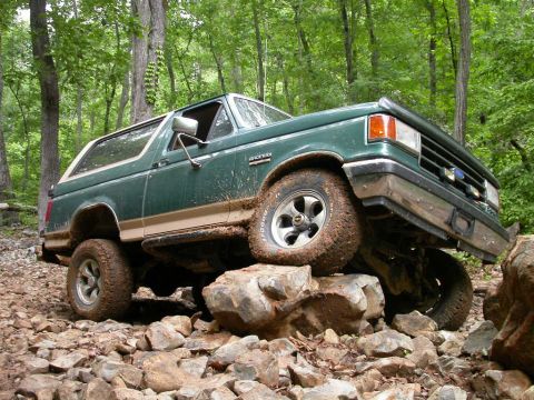 1990 Ford Bronco - This 1990 Ford Bronco navigates a challenging rocky terrain on a wooded path.