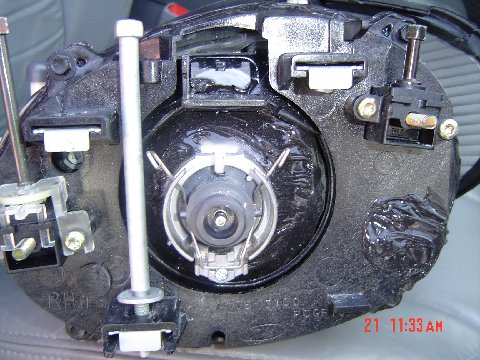 1997 Ford Taurus - Close-up view of a vehicle headlight assembly, showing internal components and mounting points.