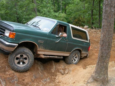 1990 Ford Bronco - 1990 Ford Bronco tackles a challenging off-road trail with steep inclines and rocks.