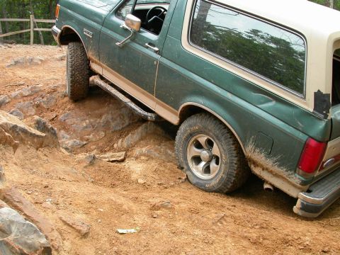 1990 Ford Bronco - A 1990 Ford Bronco navigates a challenging off-road course with steep inclines and rocks.