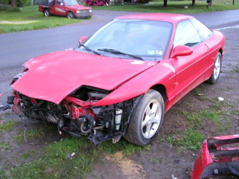 1994 Ford Probe - 1994 Ford Probe shows significant damage to its front end, parked outdoors.