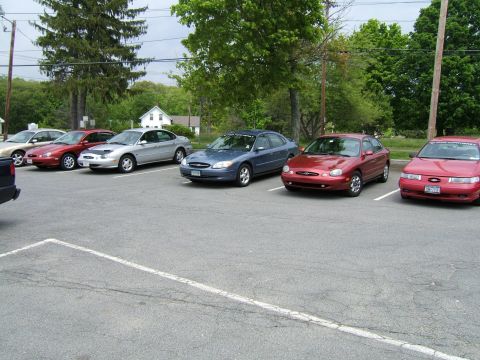 1998 Ford Taurus - A row of Ford Taurus sedans are parked in an outdoor lot on a cloudy day.