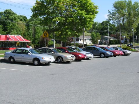 1998 Ford Taurus - A row of sedans are parked in a lot, with a McDonald's restaurant visible in the background.