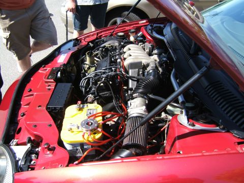 1998 Ford Taurus - Engine bay of a red car, a yellow Optima battery and custom air intake system.