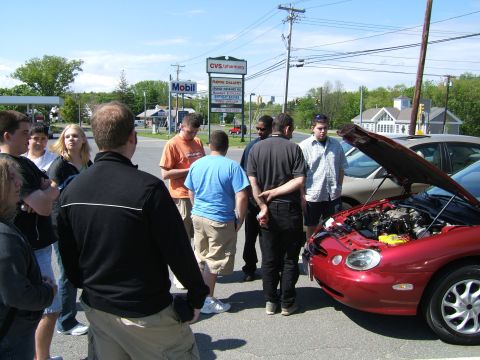 1998 Ford Taurus - A group of people examine a red 1998 Ford Taurus with its hood open.