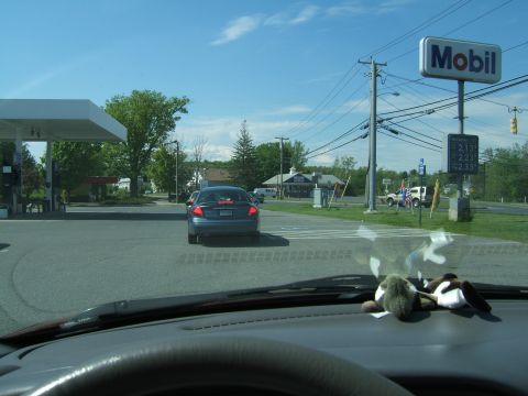 1998 Ford Taurus - A blue sedan is seen from inside a car, driving away from a gas station with a Mobil sign.