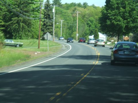 1998 Ford Taurus - A dark sedan is seen from the rear on a winding road, with several other vehicles visible ahead.