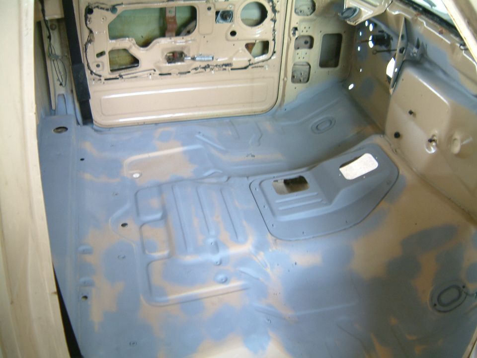 Bare primered cab floor pan and door shell during a restoration