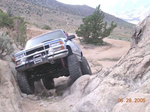 1994 Ford Bronco - A blue off-road truck is shown navigating a challenging rocky path.